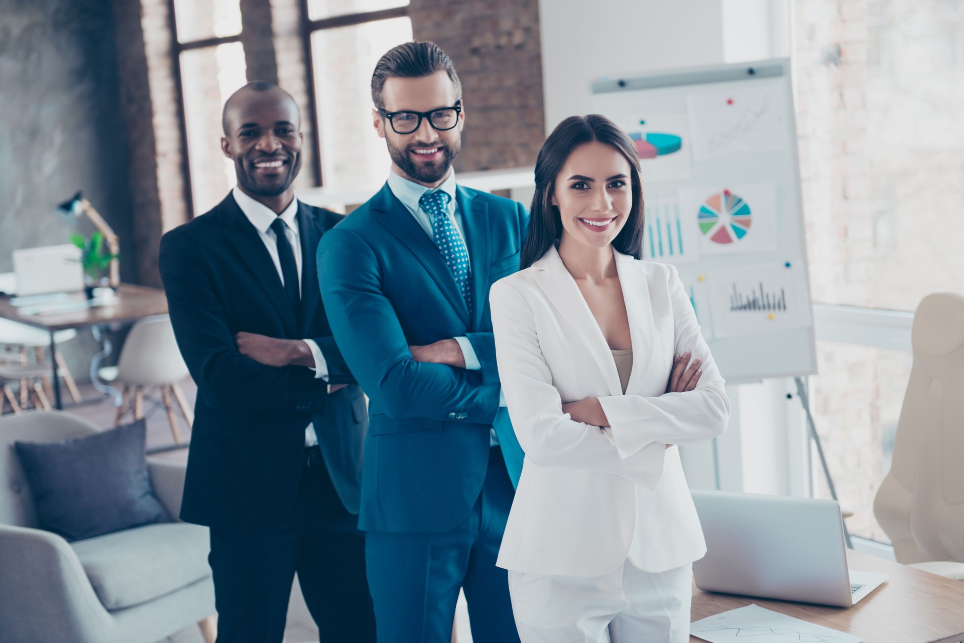 Stylish modern cheerful business trio sharks in tux, tuxedo with tie, having arms crossed, standing in work place, station, looking at camera, men with bristle and glasses and beautiful woman